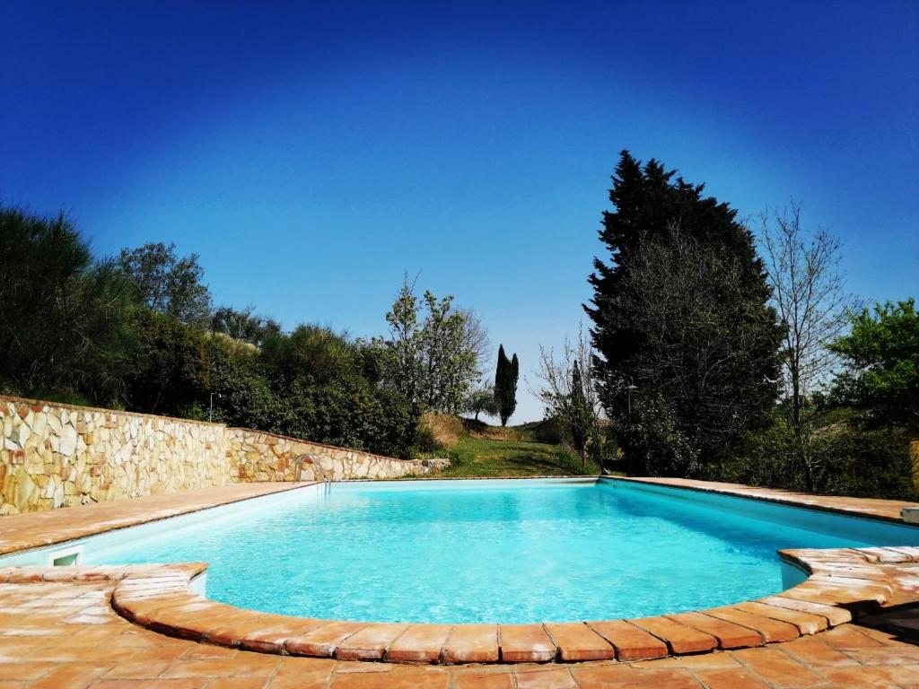 una piscina con una pared de piedra y agua azul en Viva House, en Montaione