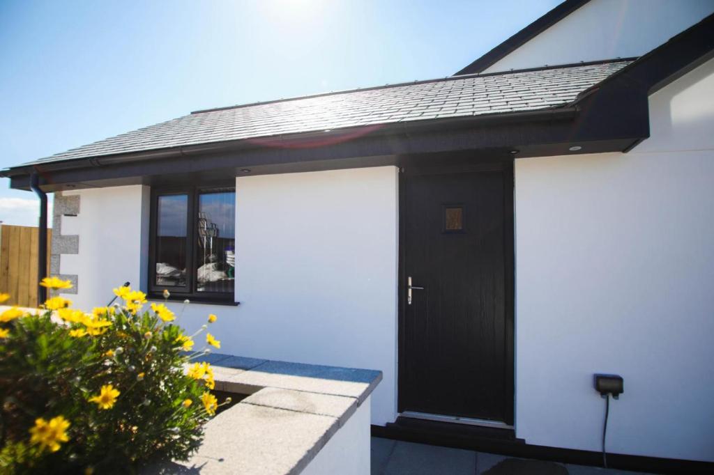 una casa en blanco y negro con dos puertas blancas de garaje en Mortham, en St Merryn