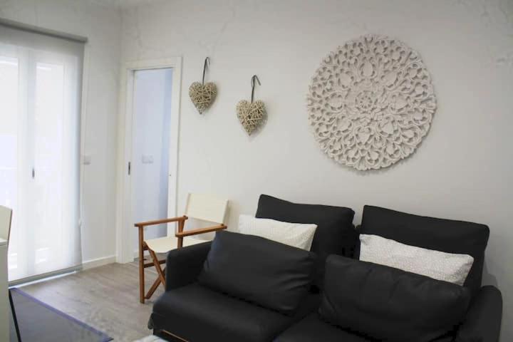 a living room with a black couch and hearts on the wall at Casa Onda Spot in Nazaré