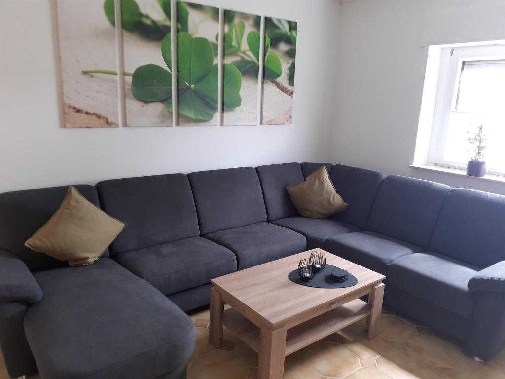 a living room with a blue couch and a coffee table at Ferienwohnung Kleeblatt in Alpen