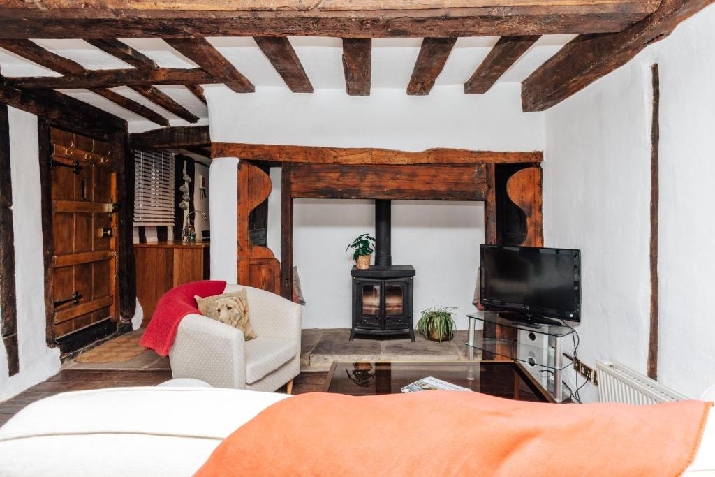 ein Wohnzimmer mit einem Bett und einem Fernseher in der Unterkunft 1400 Cottage An enchanting unique stay in Henley on Thames