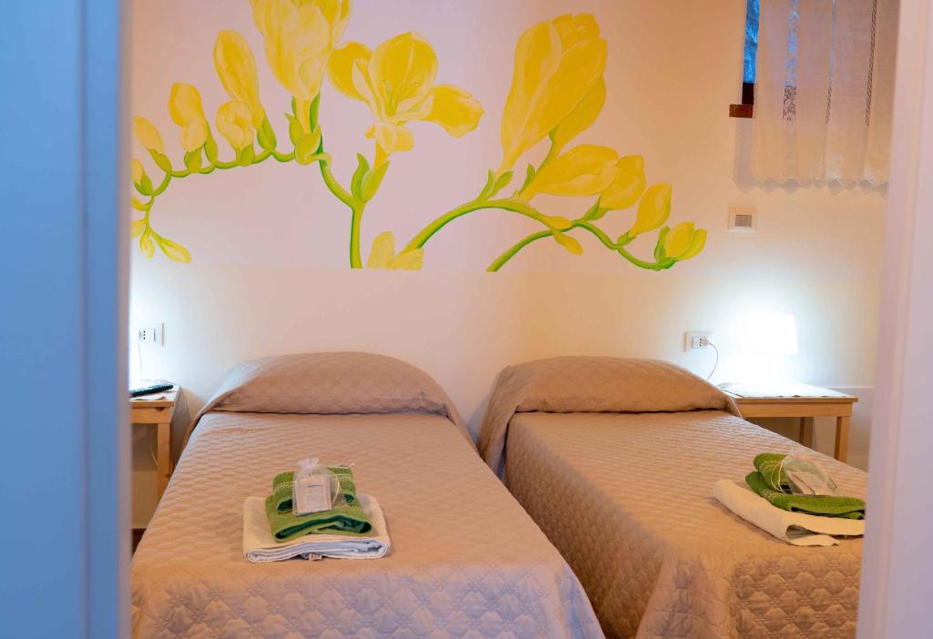 a room with two beds with yellow flowers on the wall at NOVECENTO b&b in Papasidero