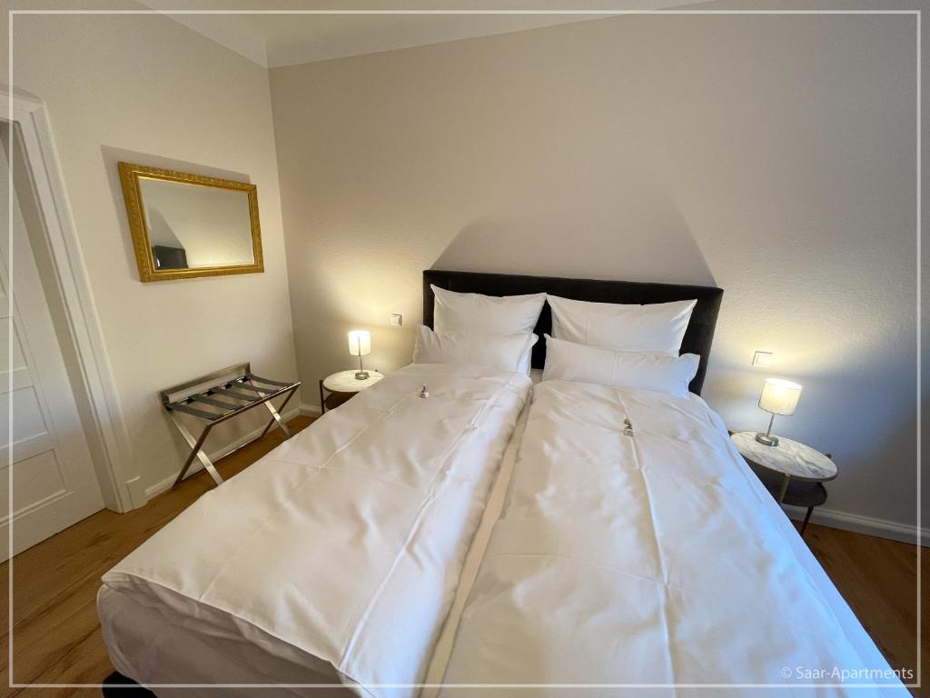 ein großes weißes Bett in einem Zimmer mit zwei Lampen in der Unterkunft Saar-Apartments in Merzig