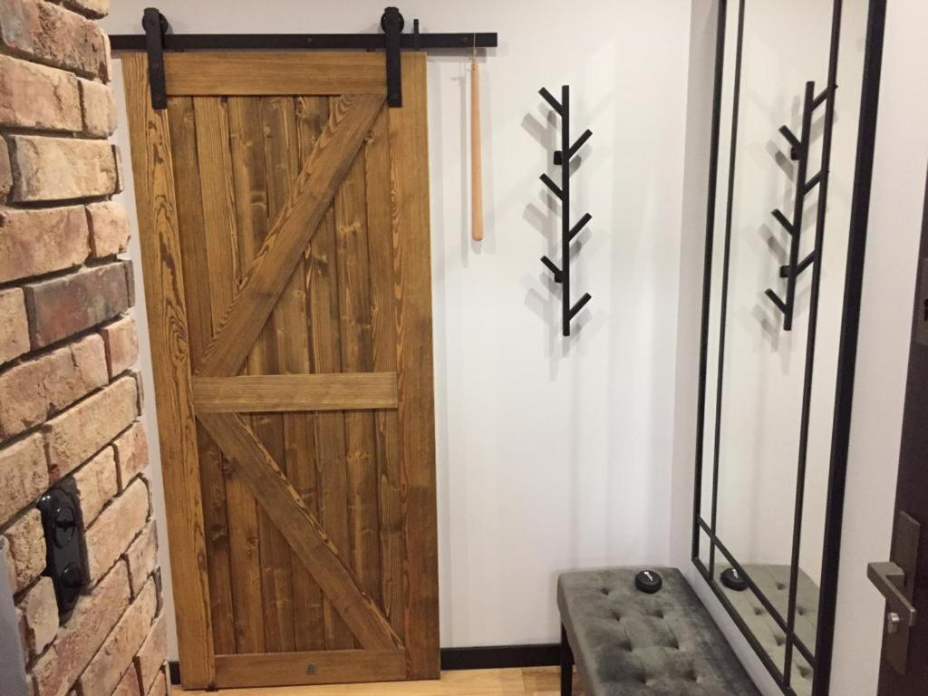 una puerta de madera con un banco junto a una pared de ladrillo en Bielsko Citylife Luxury Apartment en Bielsko-Biala