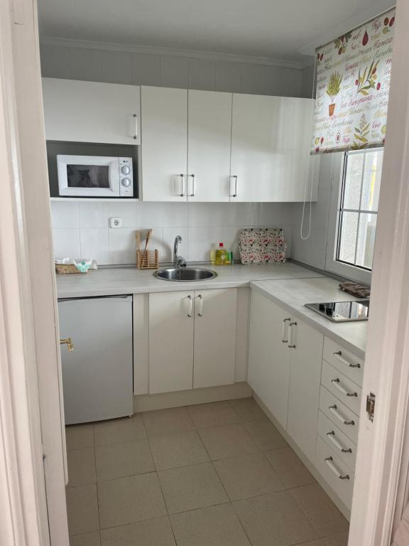 a white kitchen with a sink and a microwave at Apartamento en estación de esquí y montaña alto campoo in Brañavieja