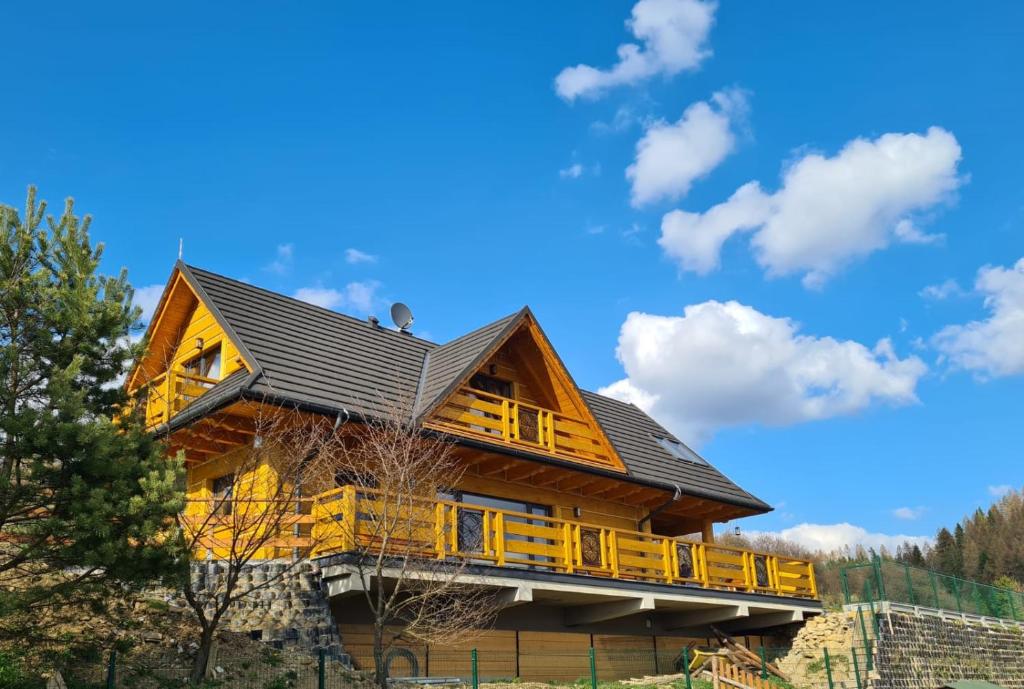 a log cabin with a deck and a blue sky at Domek Góralski nad Czorsztynem - Dom z Widokiem in Kluszkowce