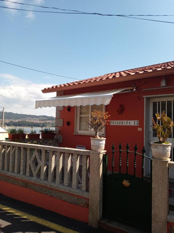 a red house with a fence and a window at A posardiña in Combarro