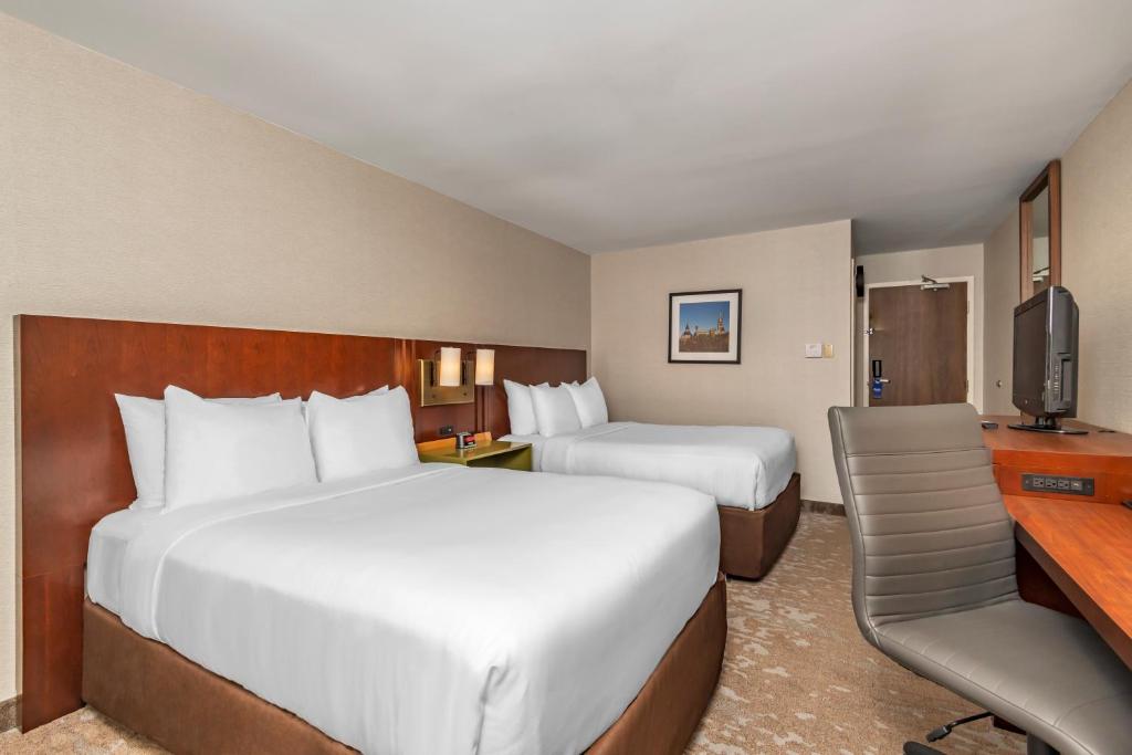 a hotel room with two beds and a desk at Comfort Inn in Ottawa
