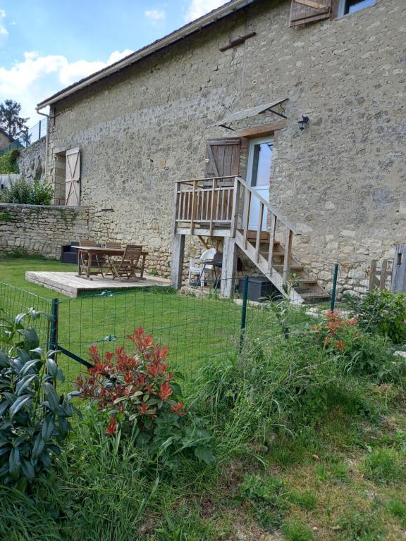 un edificio in mattoni con terrazza e panca in un cortile di La maison du colombophile a Neuville-sur-Ailette