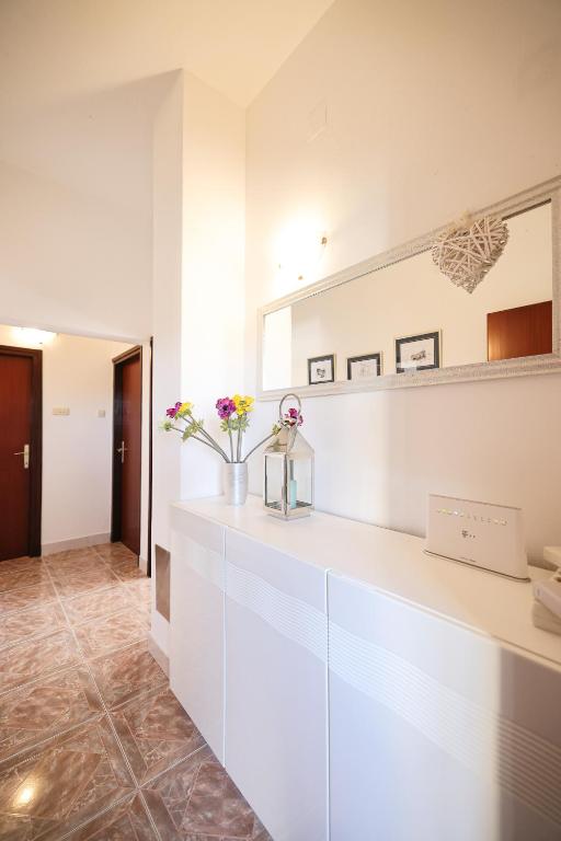a white kitchen with flowers in a vase on a counter at Apartments Marta in Verunić