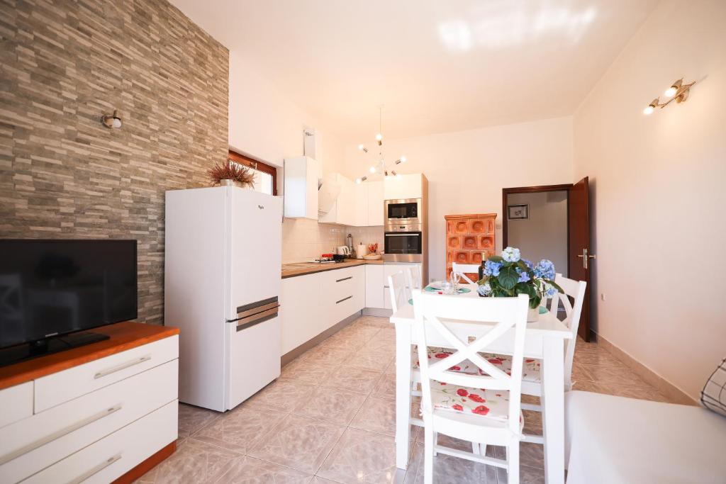 a kitchen with a white refrigerator and a table with chairs at Apartments Marta in Verunić