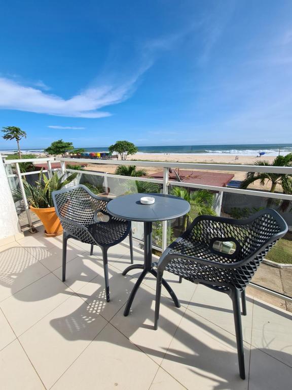 two chairs and a table on a balcony with the beach at Superbe vue sur océan in Pointe-Noire