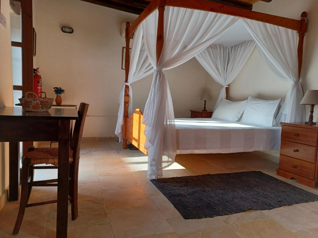 a bedroom with a canopy bed with a table and a desk at Kleanthis House in Tochni