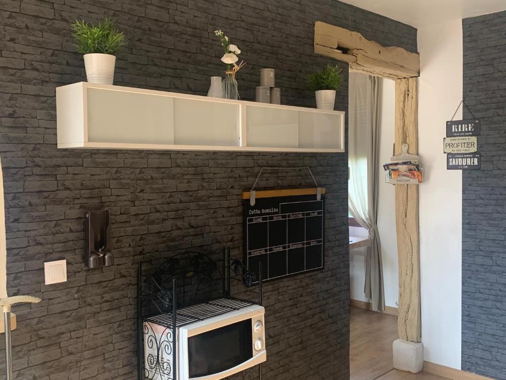 a kitchen with a microwave and a brick wall at Jojo House Les Damps n 12 in Les Damps