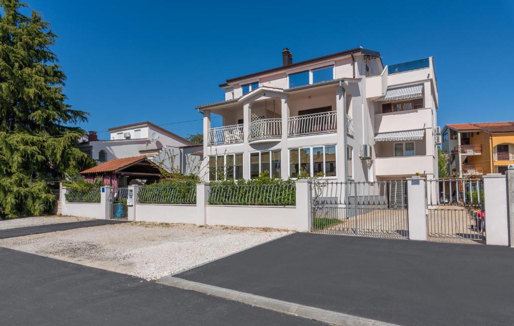 a white house with a white fence and a street at Apartments Vita in Poreč