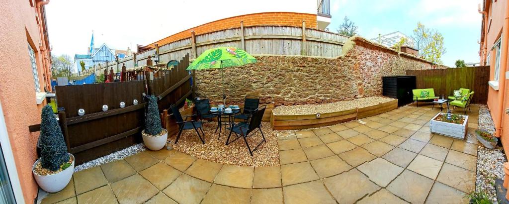 a patio with a table and a green umbrella at 24 New Esplanade Court in Paignton