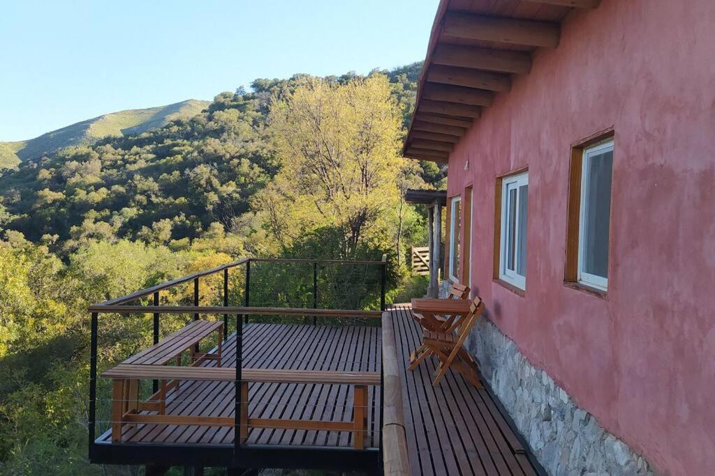 uma varanda de uma casa vermelha com uma mesa e cadeiras em Casa ecológica de montaña con vista increíble em Los Cocos