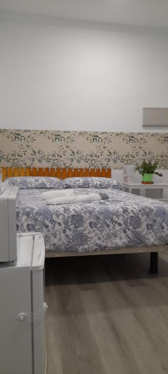 a bedroom with a bed with a blue and white blanket at El Colmenar Hospedaje in Madrid