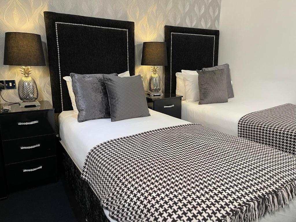 two beds with black and white sheets in a room at Sunnyside Guest House Southport in Southport