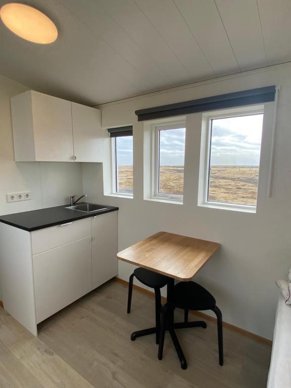 eine Küche mit einem Tisch, einem Waschbecken und 2 Fenstern in der Unterkunft Uxahryggur in Hvolsvöllur