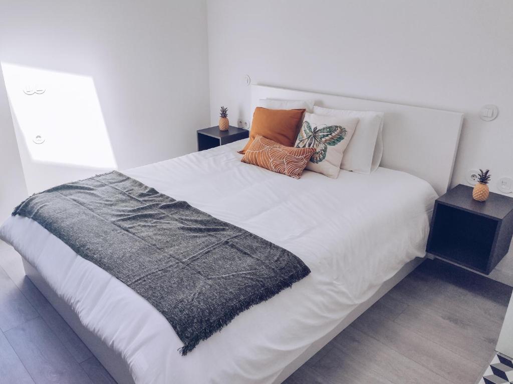 a white bed with pillows on it in a bedroom at Debaixo das Estrelas in Aveiro