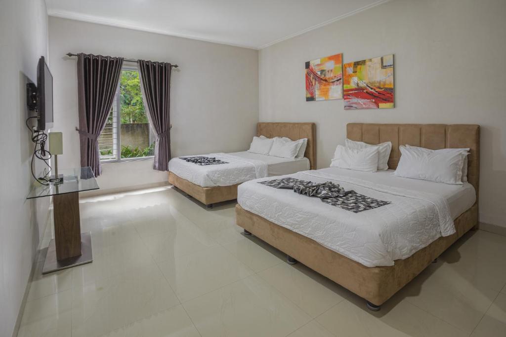 a bedroom with two beds and a flat screen tv at Villa Herrera Puncak in Puncak