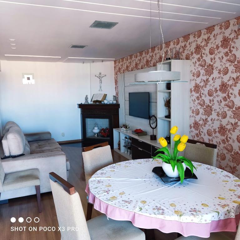 a living room with a table with yellow flowers on it at Pousada aconchegante Apartamento inteiro in São Joaquim
