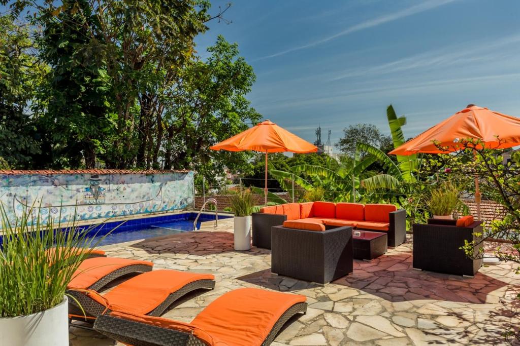 un patio con sillas y sombrillas junto a una piscina en casaJOMO Art & Food B&B en Río de Janeiro