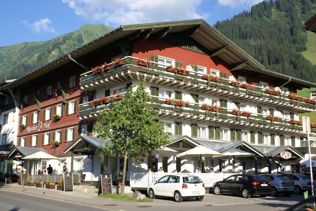 duży budynek z samochodami zaparkowanymi przed nim w obiekcie Hotel Riezler Hof w mieście Riezlern