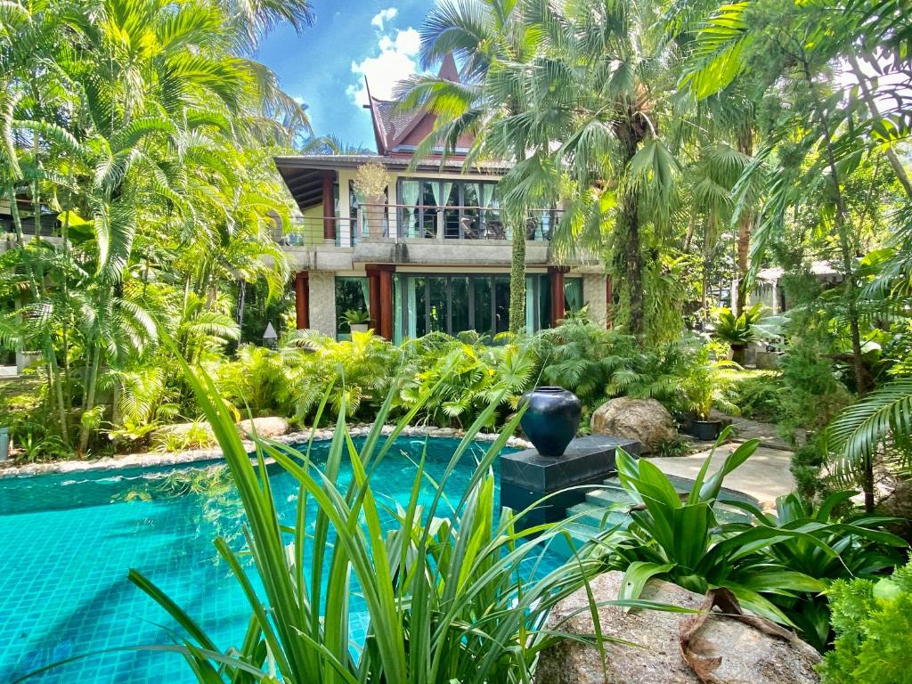 une maison avec une piscine et des palmiers dans l'établissement Villa in the Garden, Surin Beach with private spa., à Surin Beach