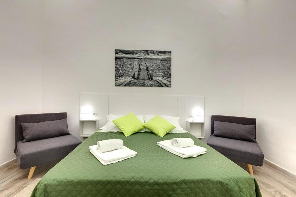 a bedroom with a green bed with two chairs at Nise Duomo apartment in Florence
