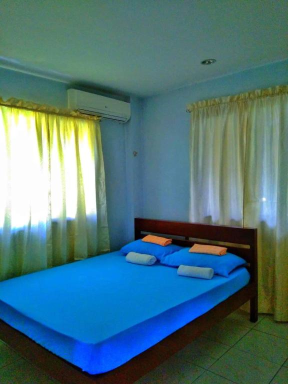 um quarto com uma grande cama azul e uma janela em D downhill'Place em Oslob