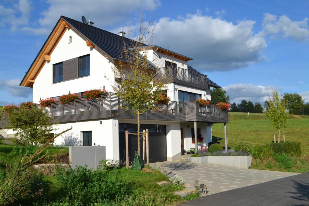una casa bianca con un balcone sopra di Zirbenholzwohnung Lochau a Eckersdorf