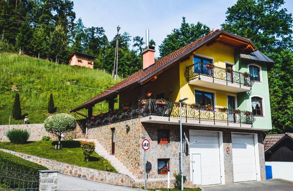 une maison jaune avec un balcon sur une colline dans l'établissement Apartmaji Krebs, à Mežica