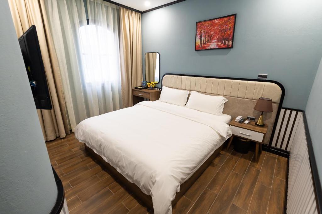 um quarto com uma cama branca e uma televisão em Hanz Boutique Hotel em Ha Long