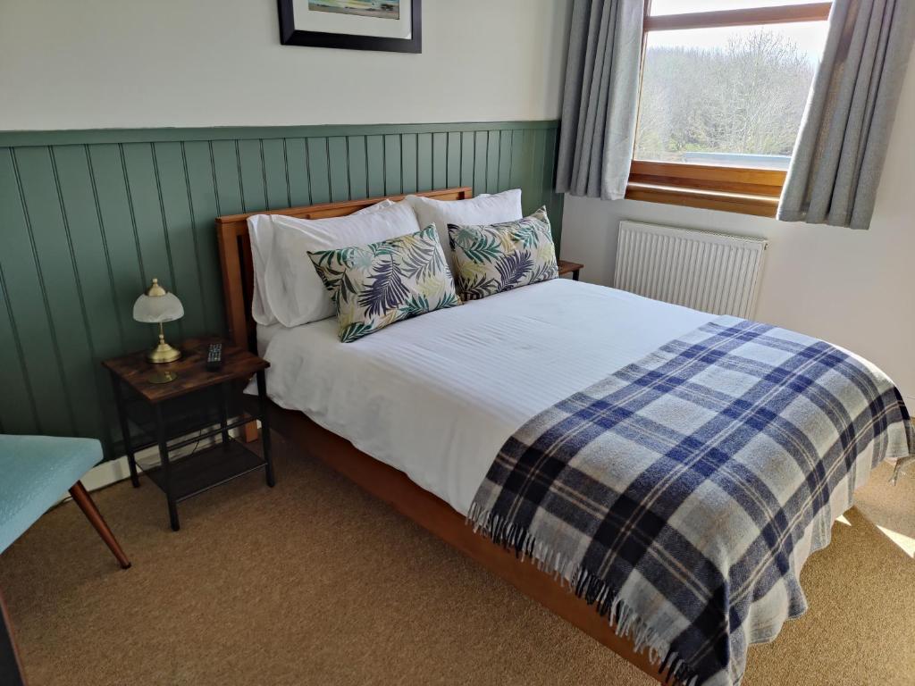 
a bed in a bedroom with a white bedspread at Edderton Lodge in Tain
