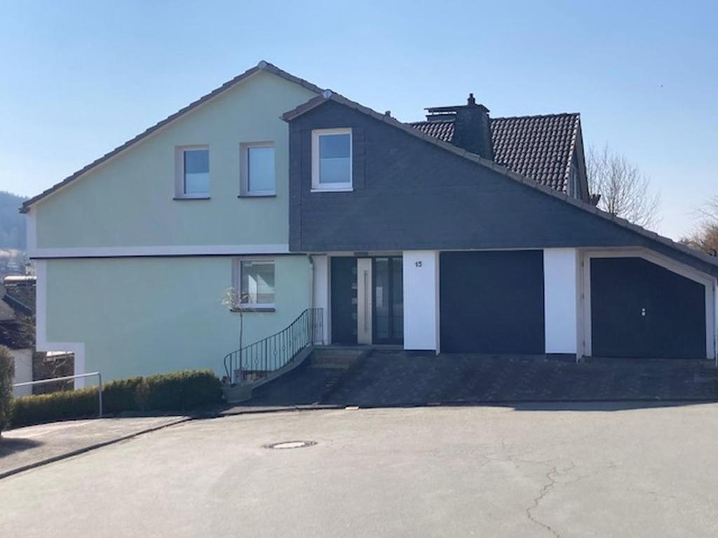 Una gran casa blanca con dos puertas de garaje. en Ferienwohnung Berg Zeit, en Olsberg