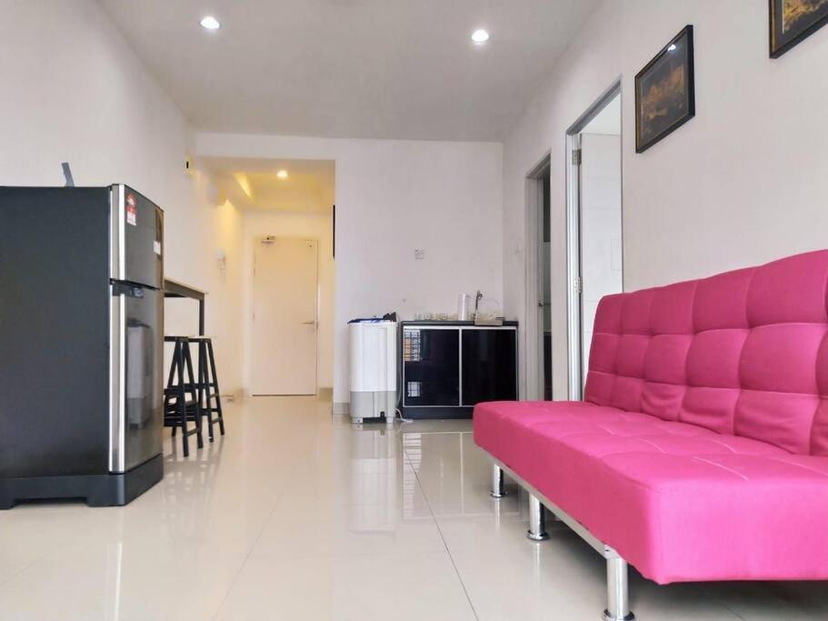 een roze bank in een woonkamer met een koelkast bij Lovely 2 bed-room Menara U Shah Alam near MSU in Shah Alam