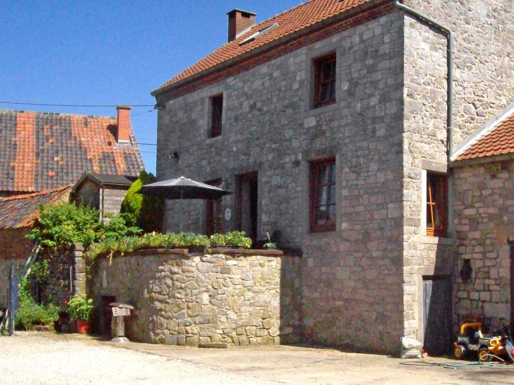 een stenen gebouw met een stenen muur en een paraplu bij Holiday Home La Bastide by Interhome in Thy-le-Bauduin
