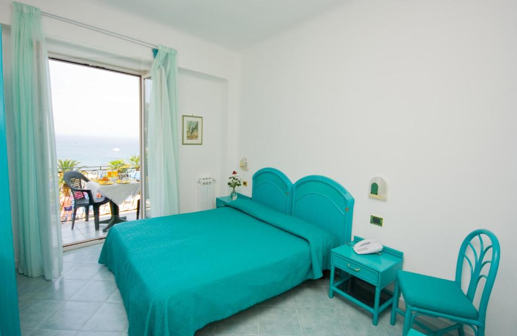 a bedroom with a blue bed and a balcony at Hotel Capizzo in Ischia