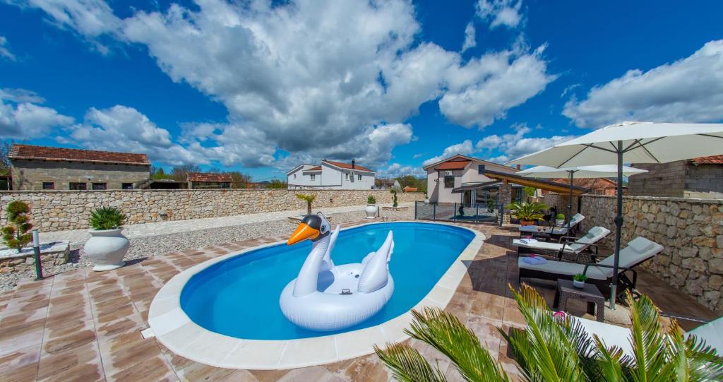 a swimming pool with an inflatable swan in a backyard at Villa Plavota in Ljubuški