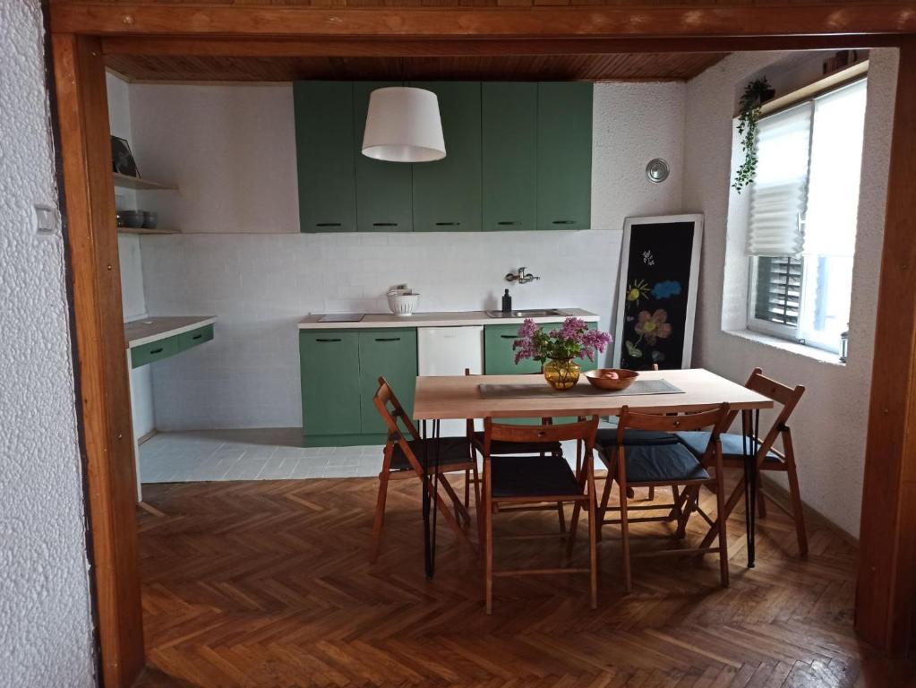 a kitchen with green cabinets and a table and chairs at Apartman Unikat in Gornja Toplica