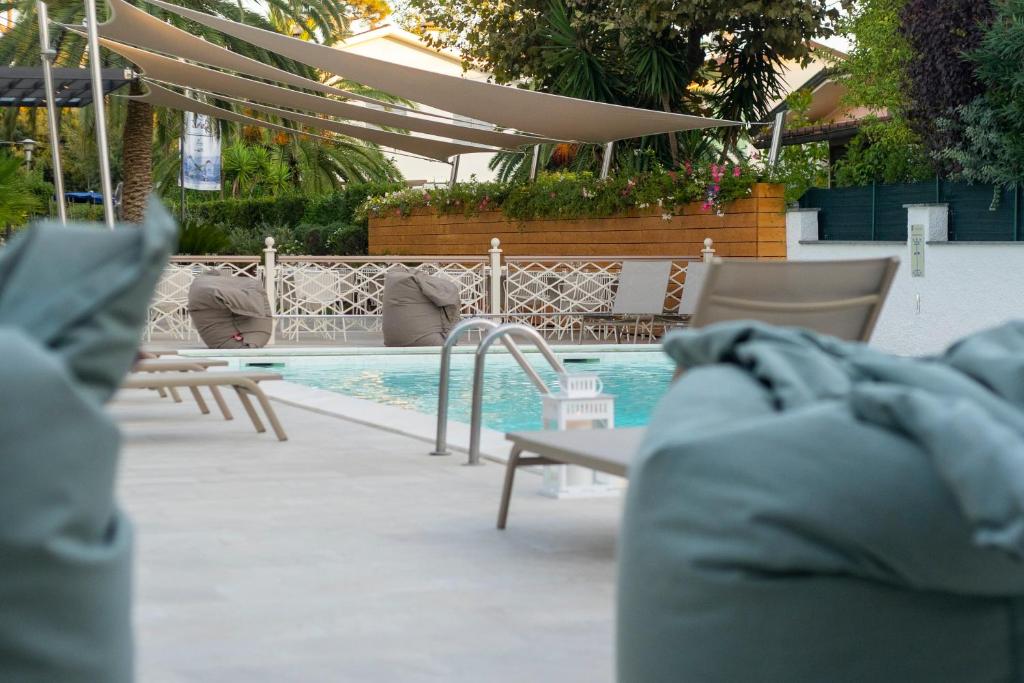 a swimming pool with chairs and a table and a swimming pool at Hotel Tarabella in Forte dei Marmi