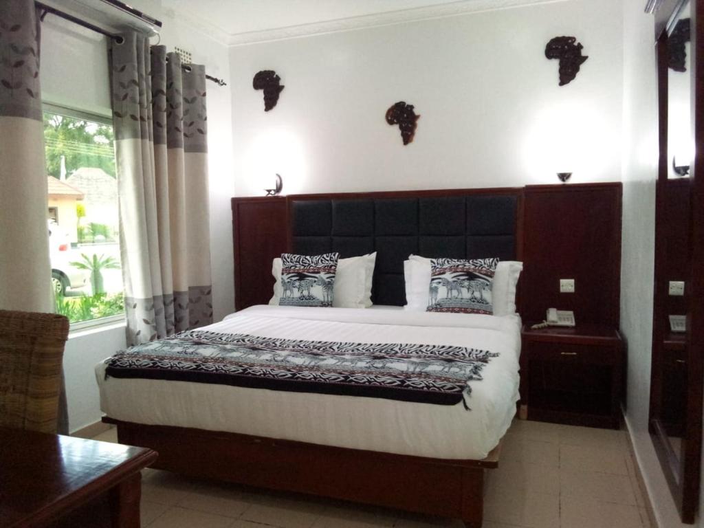 een slaapkamer met een groot bed en een raam bij Mika Lodge in Lusaka