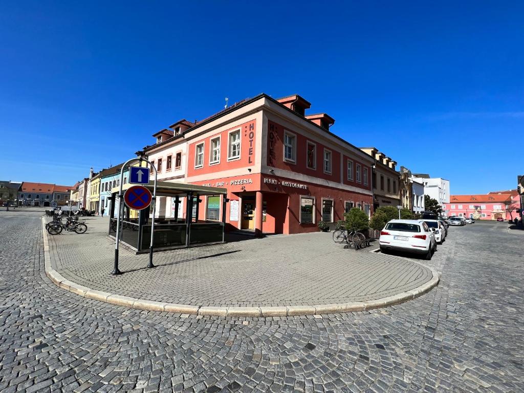 a building on a street with cars parked in front at Hotel Maxi in Uherské Hradiště