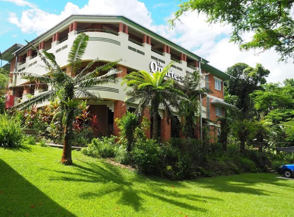 un bâtiment avec des palmiers en face de celui-ci dans l'établissement Babinda Quarters, à Babinda