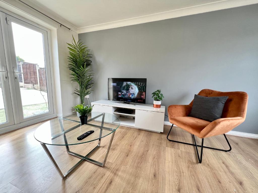 a living room with a glass table and a chair and a television at Spacious 3-Bedroom house with 5 beds and sofa-bed in Manchester