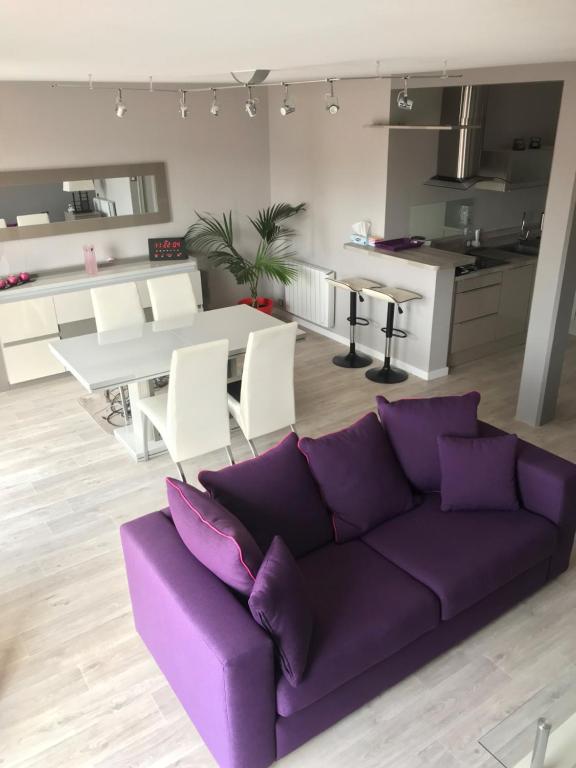 een woonkamer met een paarse bank en een keuken bij APPARTEMENT Résidence GARDENIAS SAINT JEAN DE MONTS in Saint-Jean-de-Monts