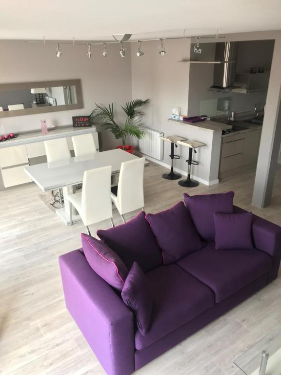 a living room with a purple couch and a kitchen at APPARTEMENT Résidence GARDENIAS SAINT JEAN DE MONTS in Saint-Jean-de-Monts