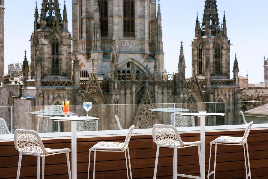 einen Balkon mit Tischen und Stühlen vor einer Kathedrale in der Unterkunft Colón Hotel Barcelona in Barcelona